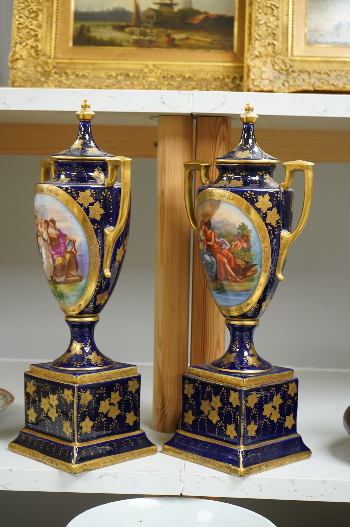 A pair of early 20th century Vienna style porcelain urns and covers, 36cm